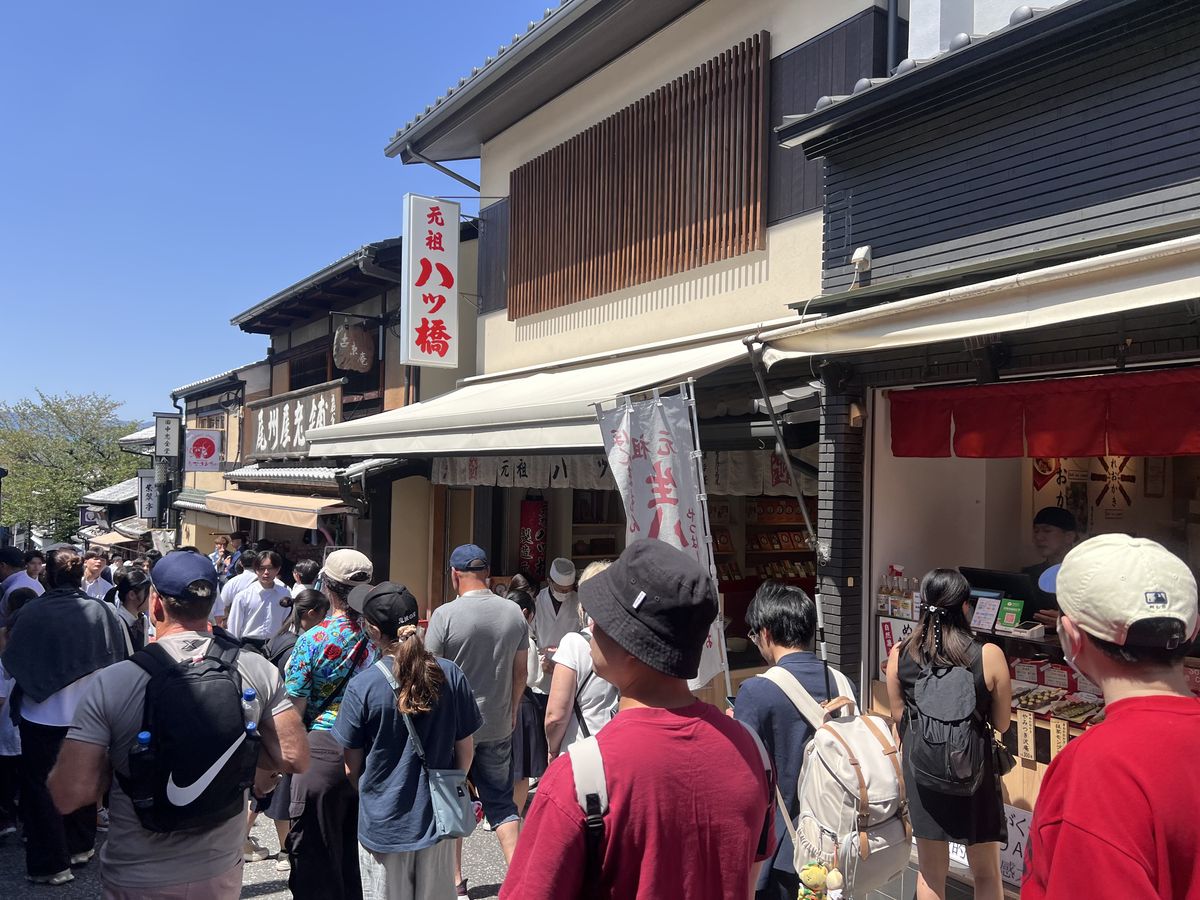 昼の清水坂。元祖八ッ橋 西尾為忠商店 清水店の店先は観光客で埋まっている