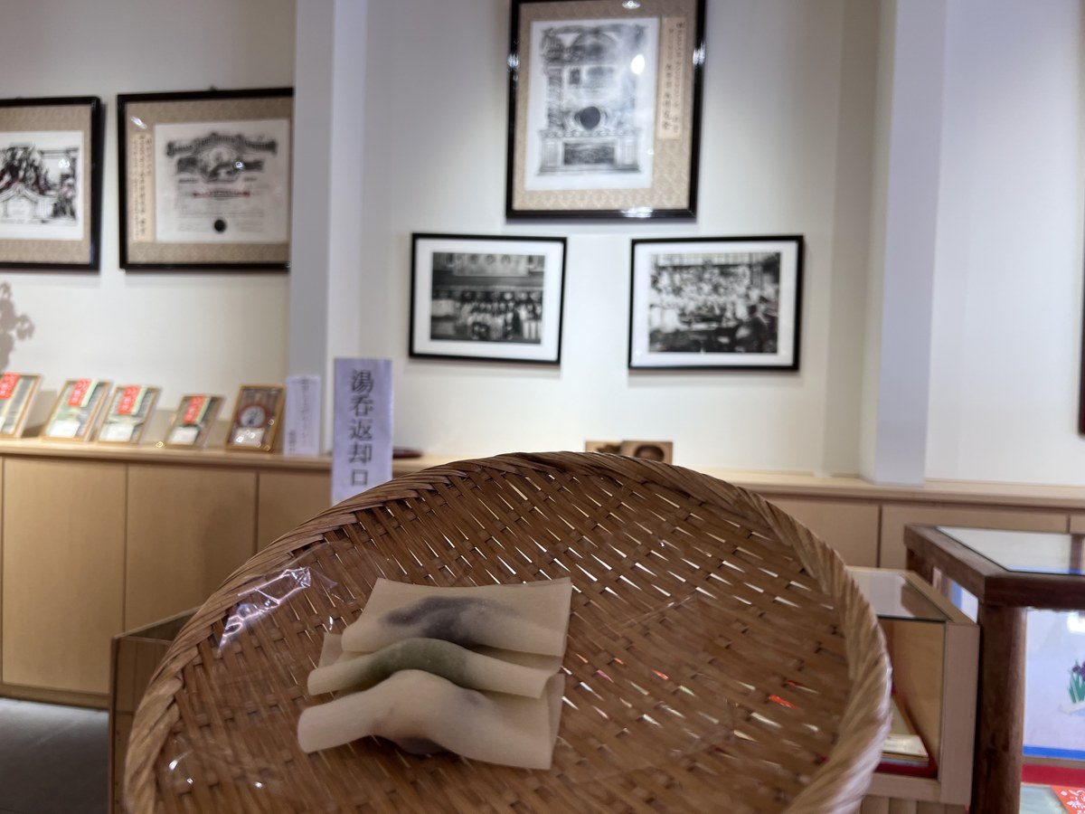 店内に立てられた「湯呑返却口」の札。奥の壁には古い賞状とモノクロの集合写真が並ぶ