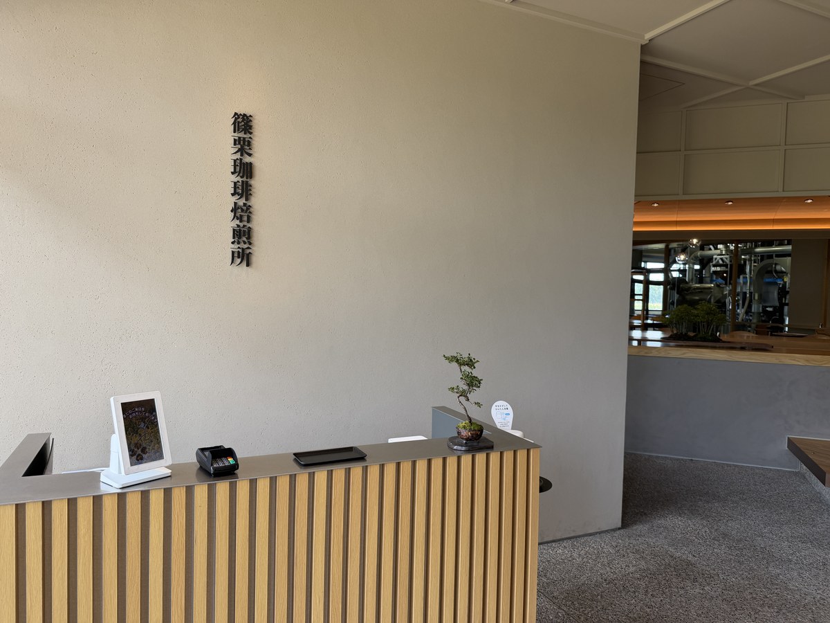 篠栗珈琲焙煎所の店内。壁に黒い切り文字の店名サインと木のルーバーのカウンター