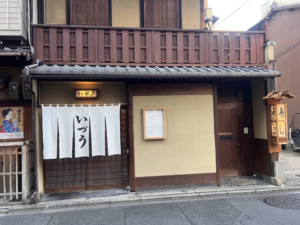 祇園いづうの店構え。瓦庇の下に白い暖簾と木の看板