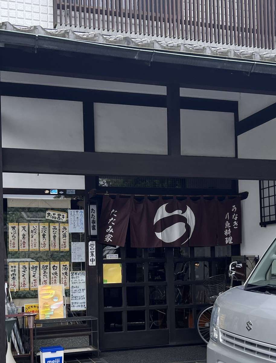 割烹川魚料理 たたみ家の外観。濃い茶色の暖簾に白く抜いた店章