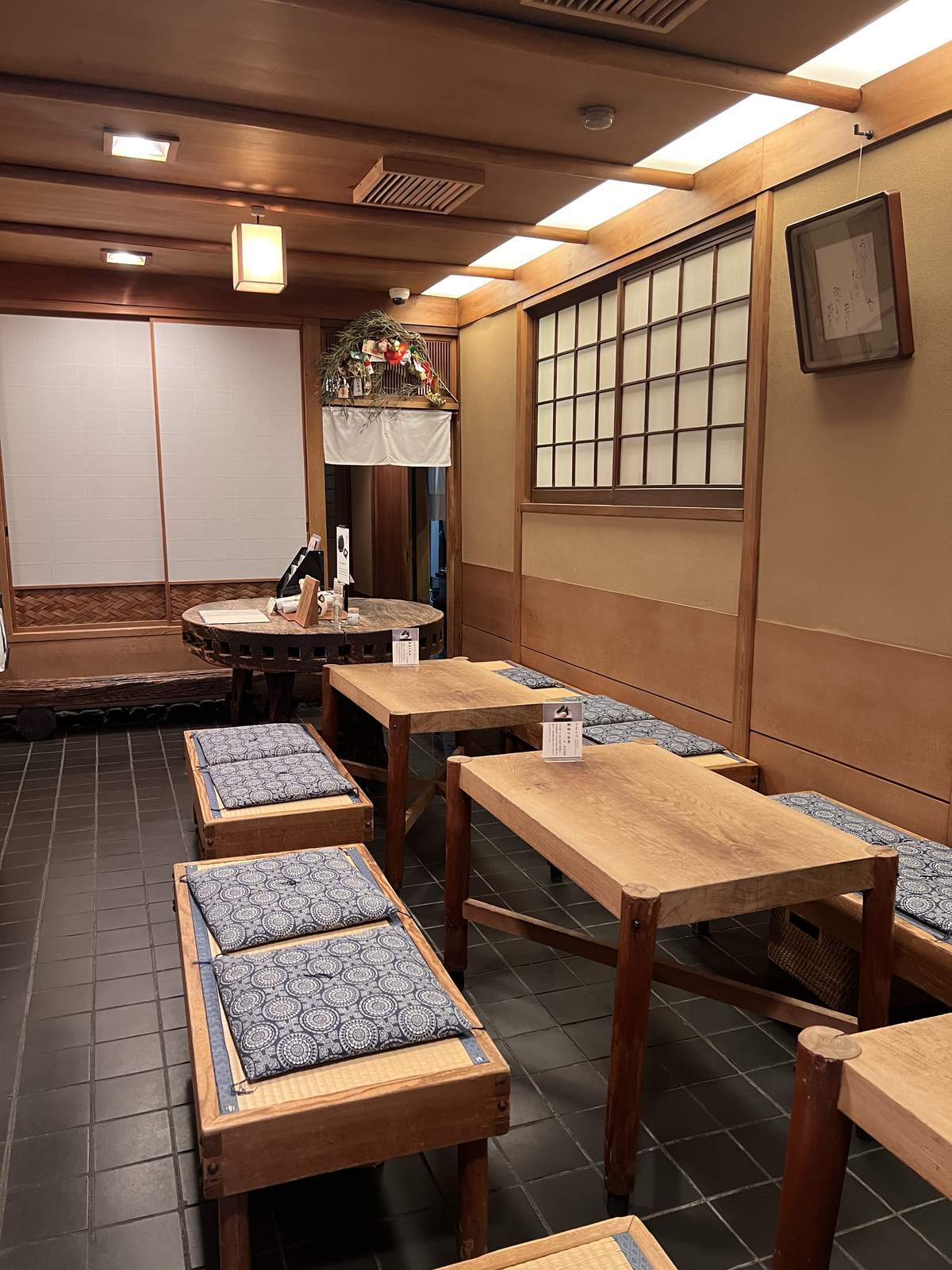 いづうの店内。木のテーブルと藍の座布団を載せたベンチが並ぶ